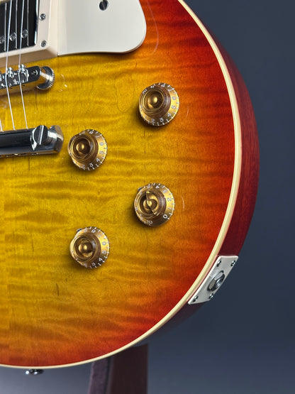 Close-up of a sunburst electric guitar with four tuning pegs on a dark background