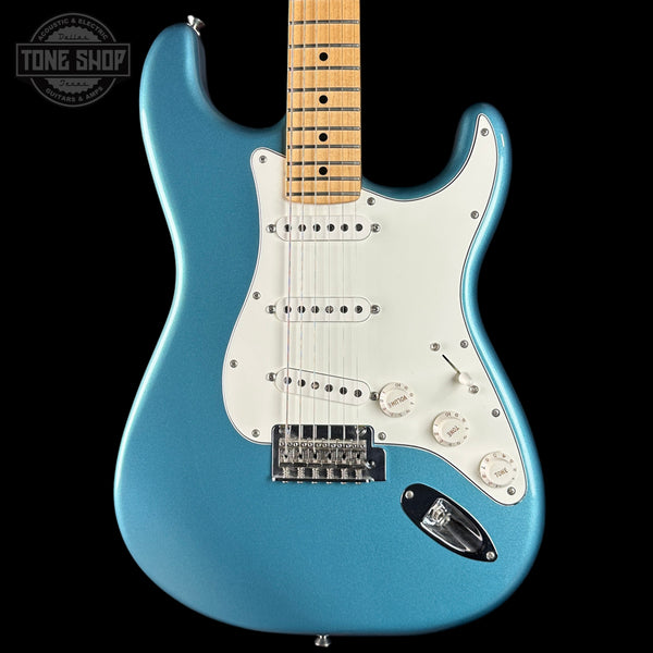 Blue electric guitar with a white pickguard on a black background, featuring 'Tone Shop' branding.