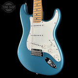 Blue electric guitar with a white pickguard on a black background, featuring the Tone Shop logo.
