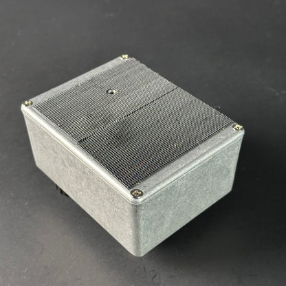 Metallic box with mesh cover on a dark gray background