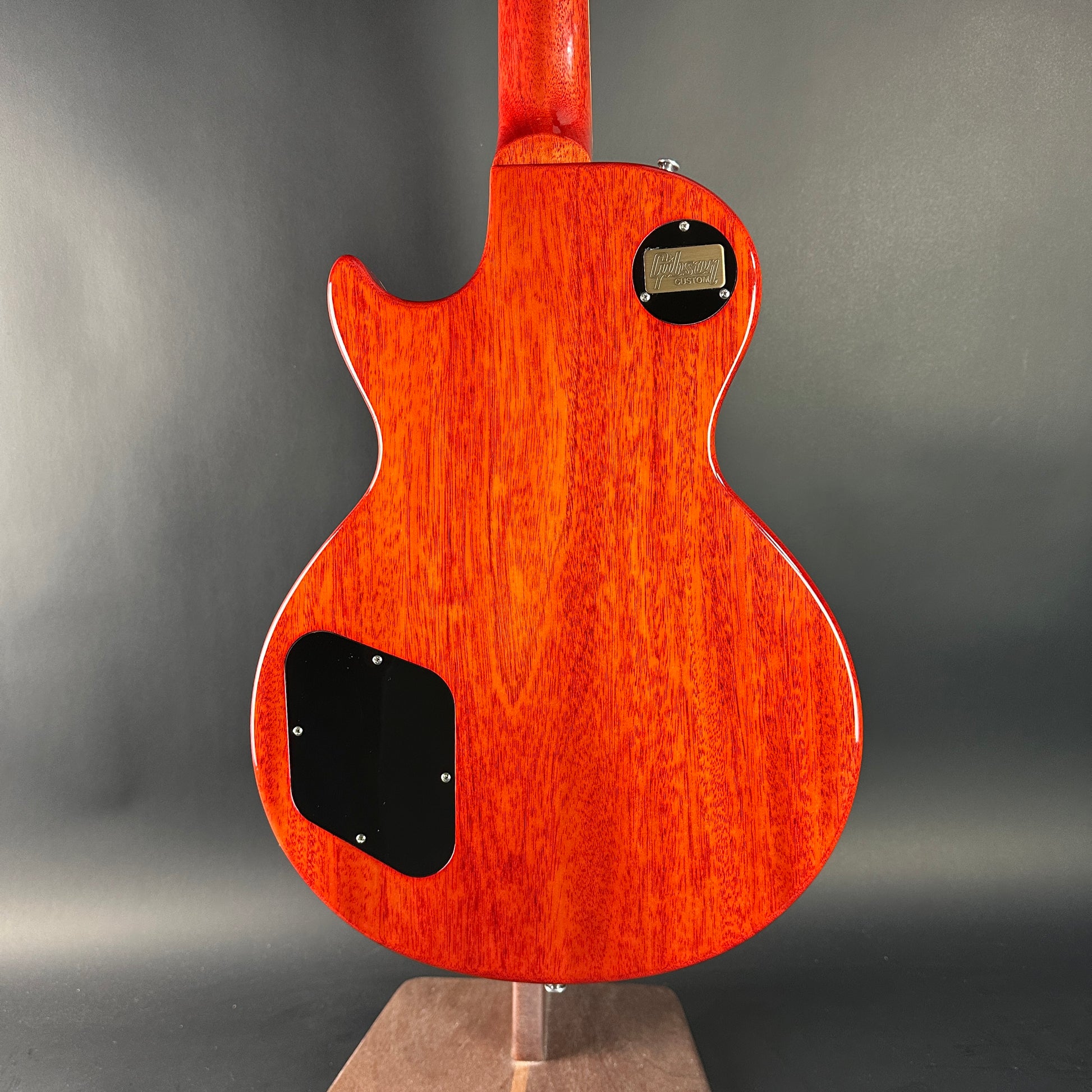 Wooden electric guitar on a stand with a gray background