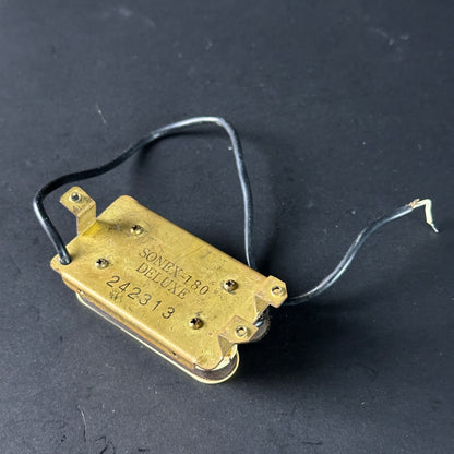 Brass guitar pickup with visible branding on a dark background