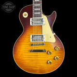 A classic electric guitar with a natural sunburst finish, featuring a cream pickguard, chrome hardware, and gold control knobs, shown against a solid black background.