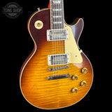 A classic electric guitar with a natural flame maple top, showing a warm orange-brown sunburst finish. It features a cream pickguard, chrome hardware, and gold-toned control knobs, set against a solid black background with a Tone Shop watermark in the upper left corner.