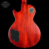 The back of a Gibson Les Paul Custom '59 electric guitar with a glossy reddish-brown cherry wood finish, shown against a solid black background. Features a circular chrome 'Gibson Les Paul Custom '59' badge and a black plate on the lower back.