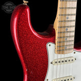 Close-up of a red glitter electric guitar body with a maple fretboard and white pickguard against a black background. A Tone Shop watermark is visible in the top left corner.