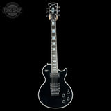 A black electric guitar with white trim and light blue block inlays, shown vertically against a solid black background. A Tone Shop watermark is visible in the top-left corner.