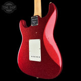 Rear view of a Fender Stratocaster electric guitar with a red glitter finish, a light wood neck, and a white pickguard, shown against a black background.