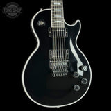 A black electric guitar with chrome hardware and a white binding, shown against a solid black background. A 'TONE SHOP' watermark is visible in the top-left corner.
