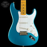 A turquoise blue electric guitar with a white pickguard and maple neck, photographed against a solid black background. A Tone Shop watermark is visible in the top-left corner.