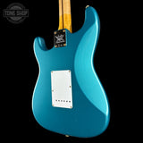 The back of a turquoise blue electric guitar with a white pickguard and a black hardware plate, shown against a solid black background.