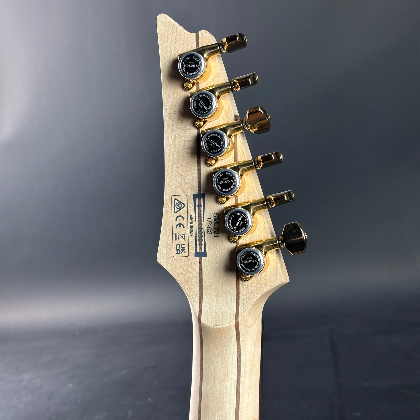 Guitar headstock with tuning pegs on a dark gray background