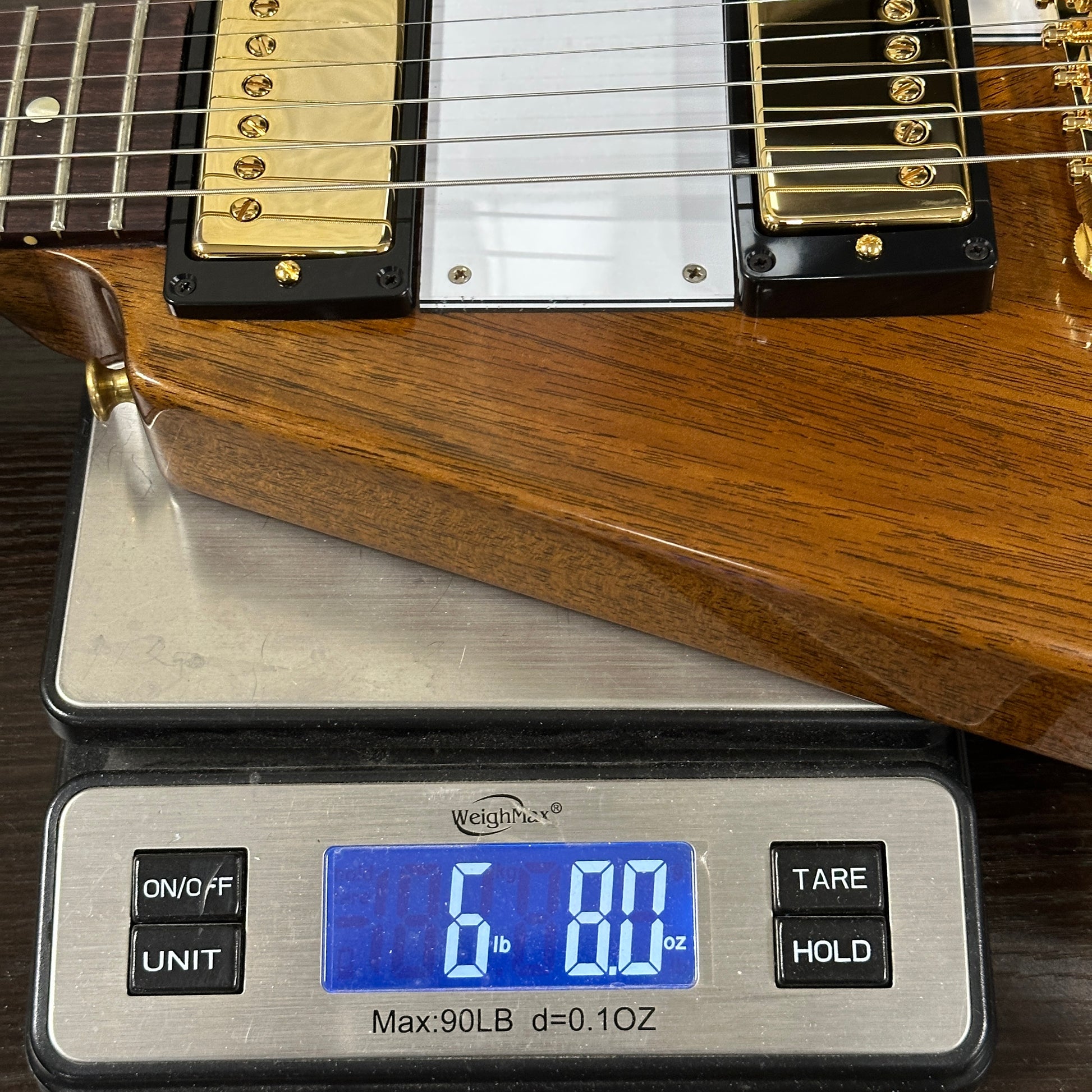 Wooden guitar on a digital scale displaying weight