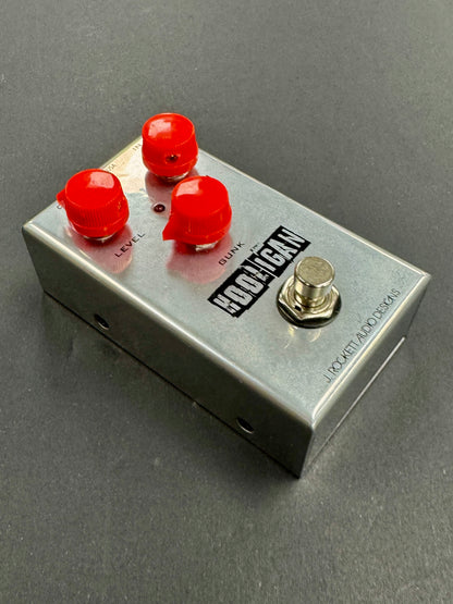 Guitar effects pedal with red knobs and a silver body on a gray background