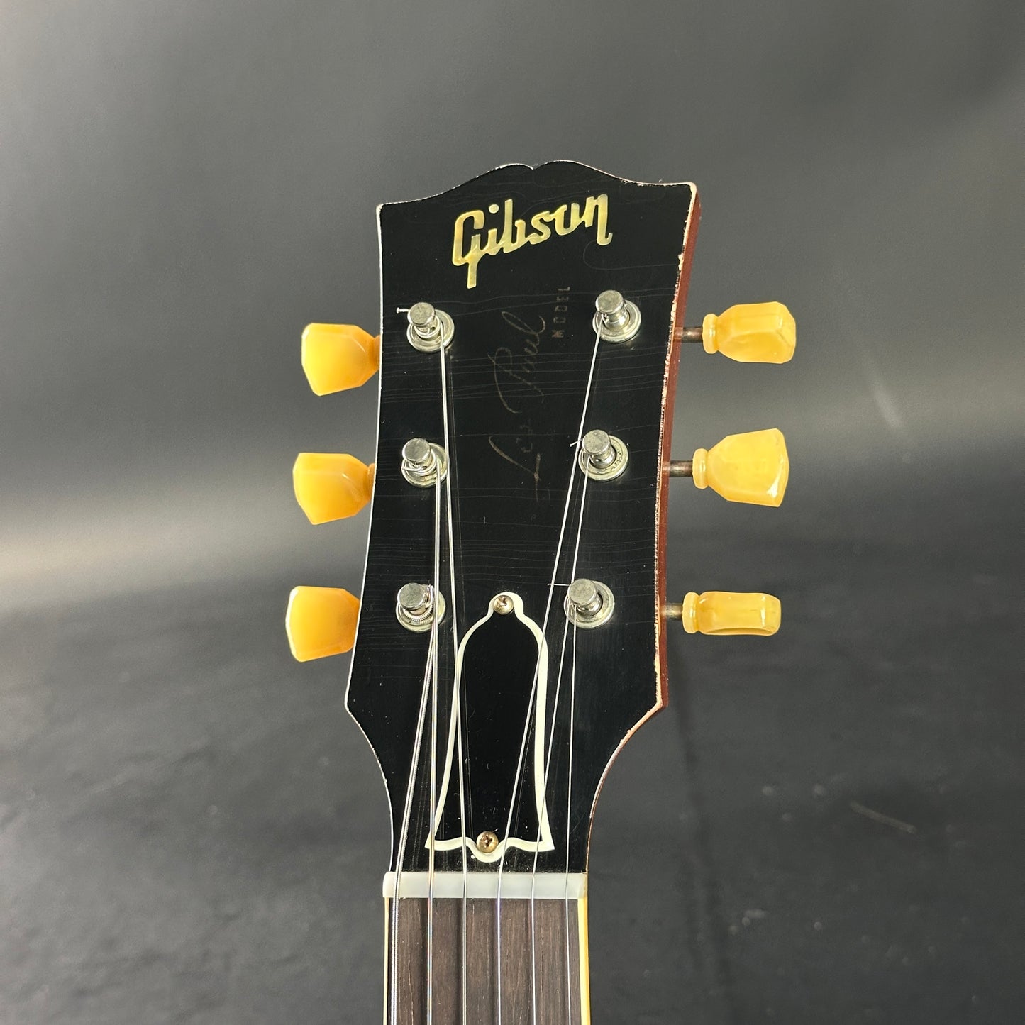 Gibson guitar headstock with yellow tuning pegs on a dark background