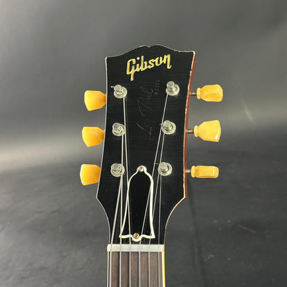 Gibson guitar headstock with yellow tuning pegs on a dark background