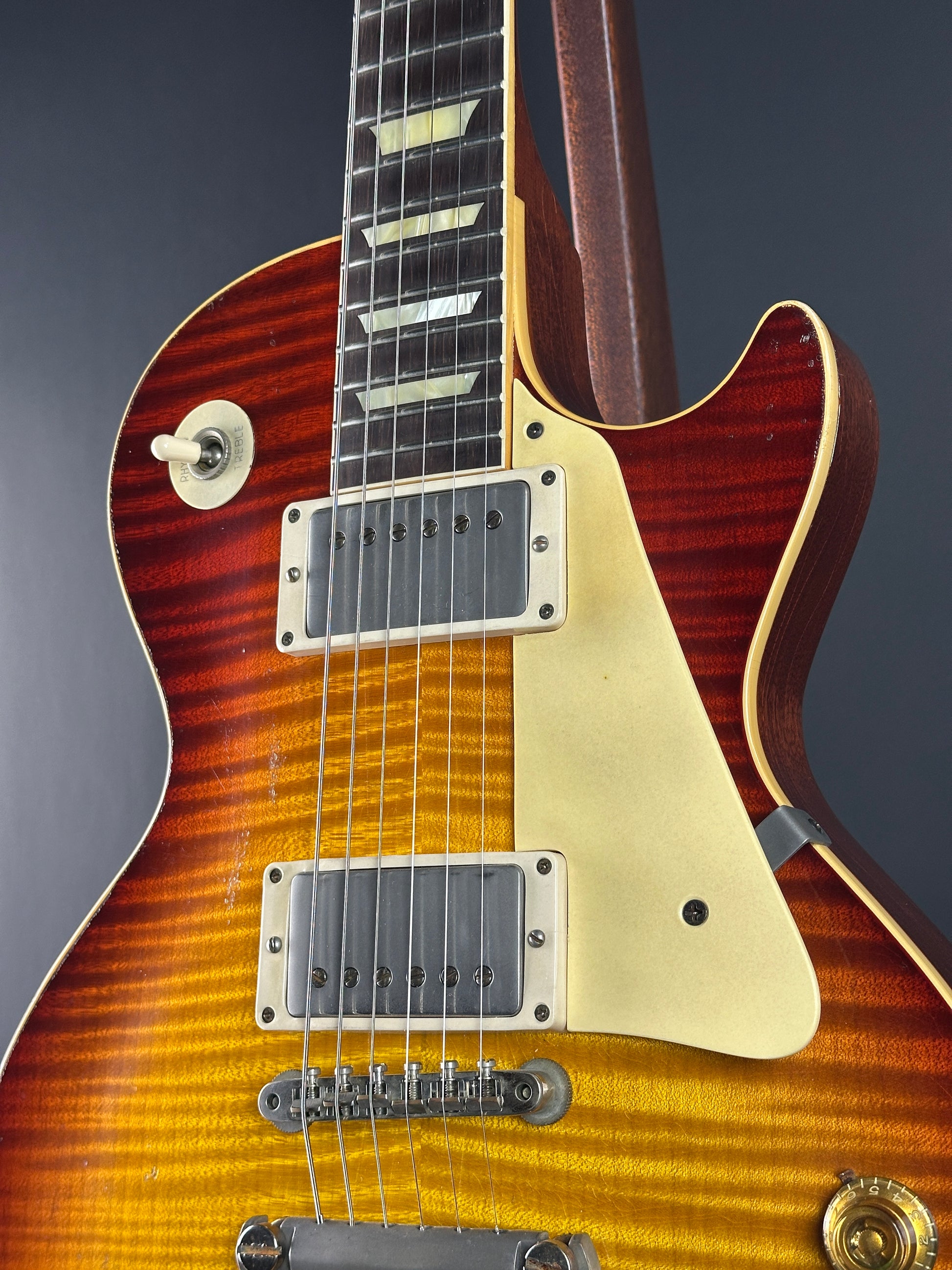 Close-up of a Les Paul electric guitar with a sunburst finish on a dark background