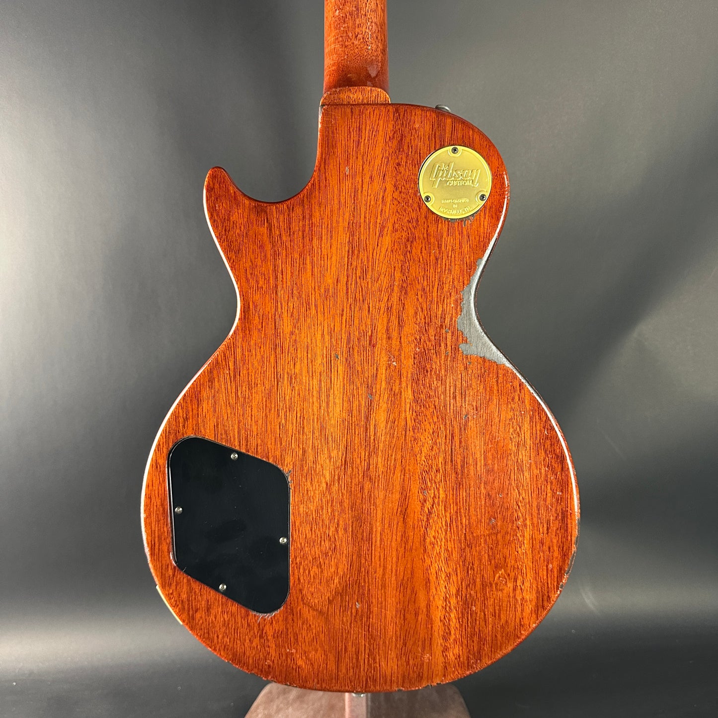 Back view of a wooden electric guitar with a visible brand logo on a dark background