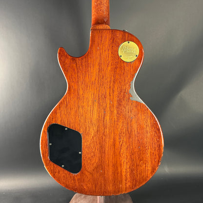 Back view of a wooden electric guitar with a visible brand logo on a dark background