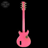 A pink electric guitar shown from the back against a solid black background, featuring a distressed finish with gold-toned hardware and a Tone Shop watermark in the upper left corner.