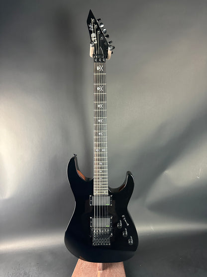 Black electric guitar on a gray background