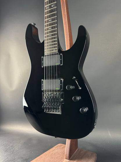 Black electric guitar on a reflective surface with a neutral background
