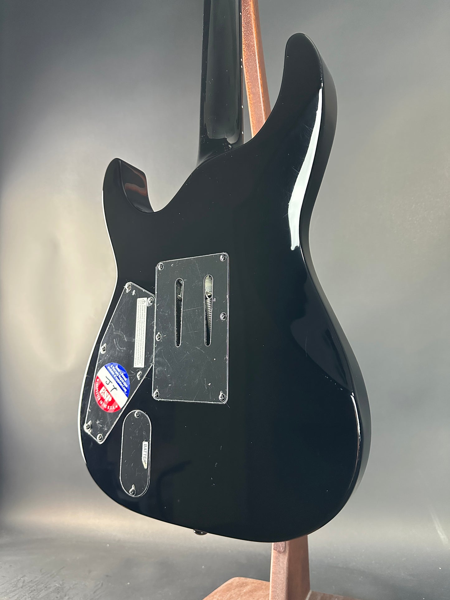 Black electric guitar body with visible brand labels on a gray background