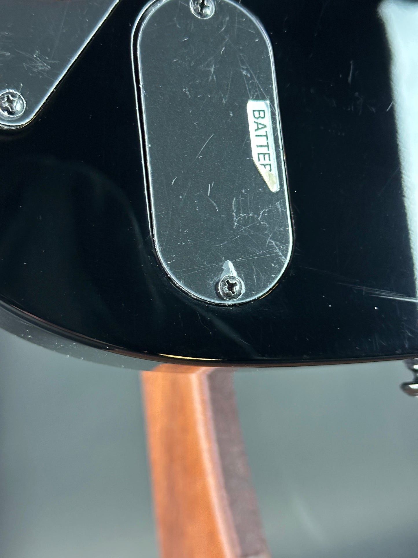 Close-up of a guitar with 'Batter' branding on a black surface.
