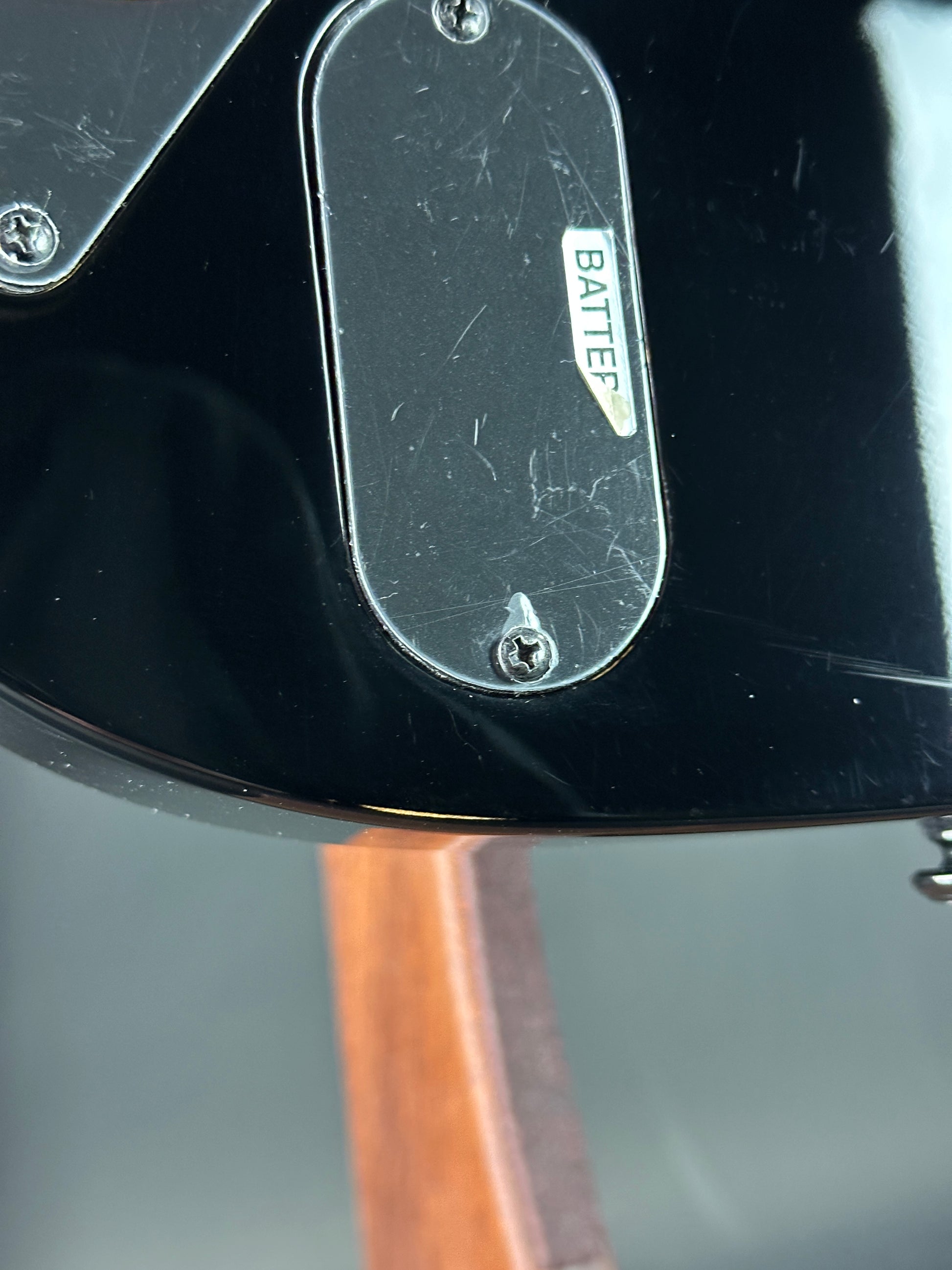 Close-up of a guitar with 'Batter' branding on a black surface.
