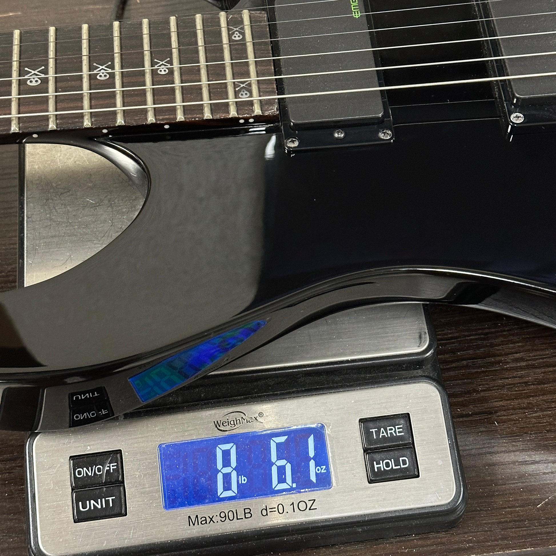 Black electric guitar on a digital scale displaying weight