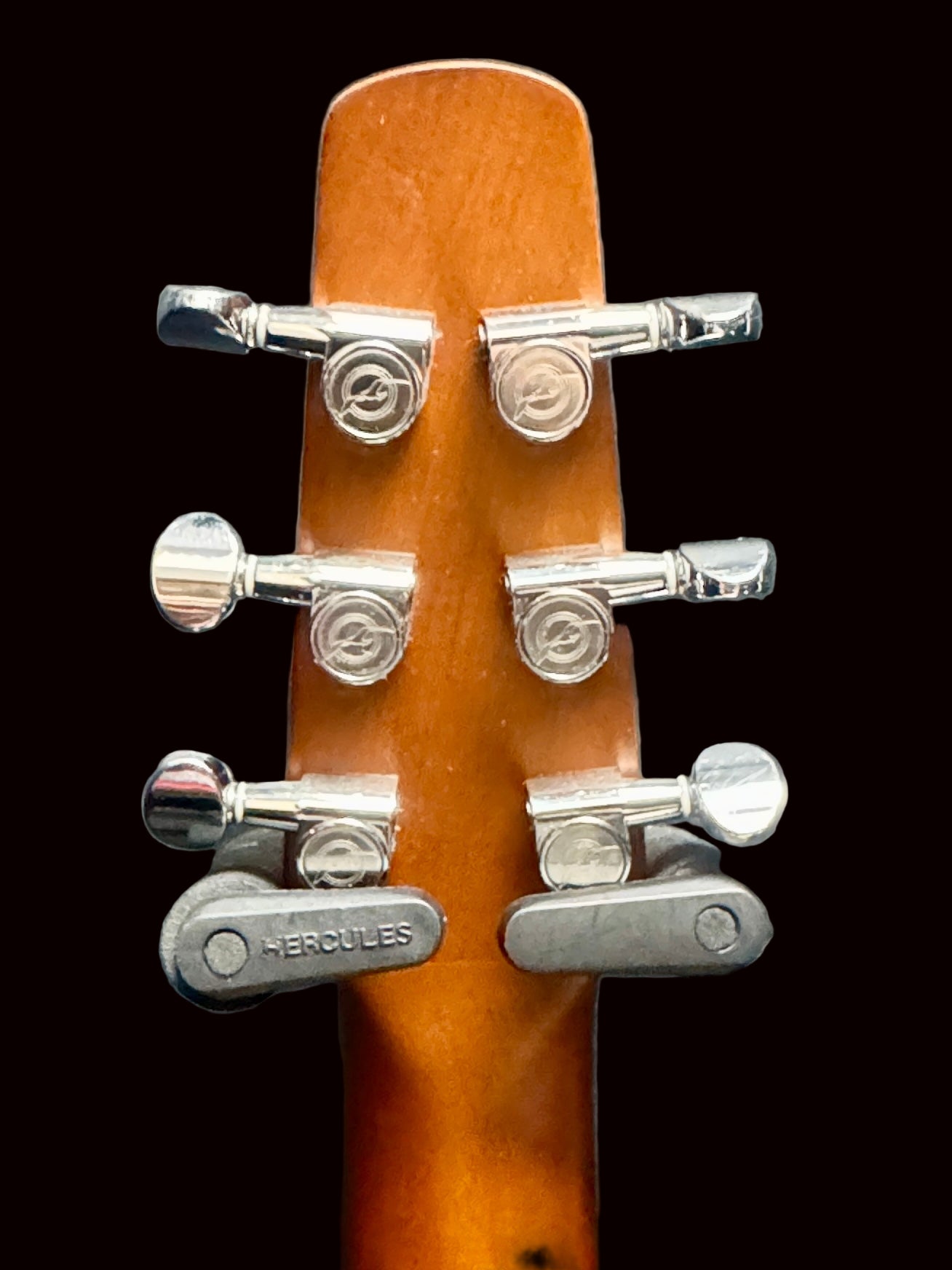 Guitar headstock with tuning pegs on a gray background