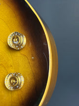 Close-up of a guitar's headstock with tuning pegs against a dark background