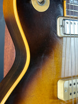 Close-up of a guitar's neck and fretboard with a sunburst finish.