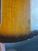 Close-up of a guitar's wooden neck with visible scratches and wear.