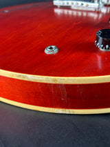Close-up of a red guitar with a visible brand logo on a dark background