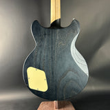 Back view of a blue electric guitar with a yellow pickguard on a dark gray background