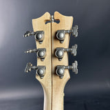 Close-up of a guitar headstock with tuning pegs on a dark gray background