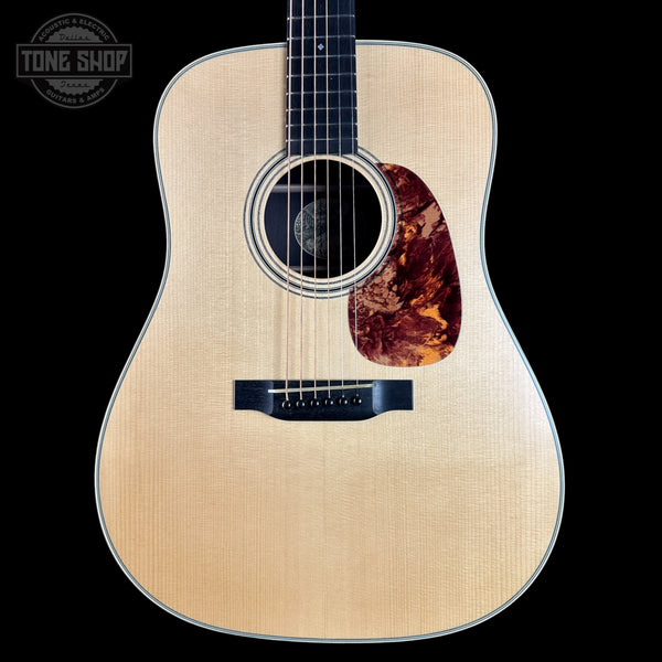 Acoustic guitar with a tortoiseshell pickguard on a black background, featuring the Tone Shop logo.