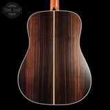 Wooden acoustic guitar back with a visible brand logo in the corner.
