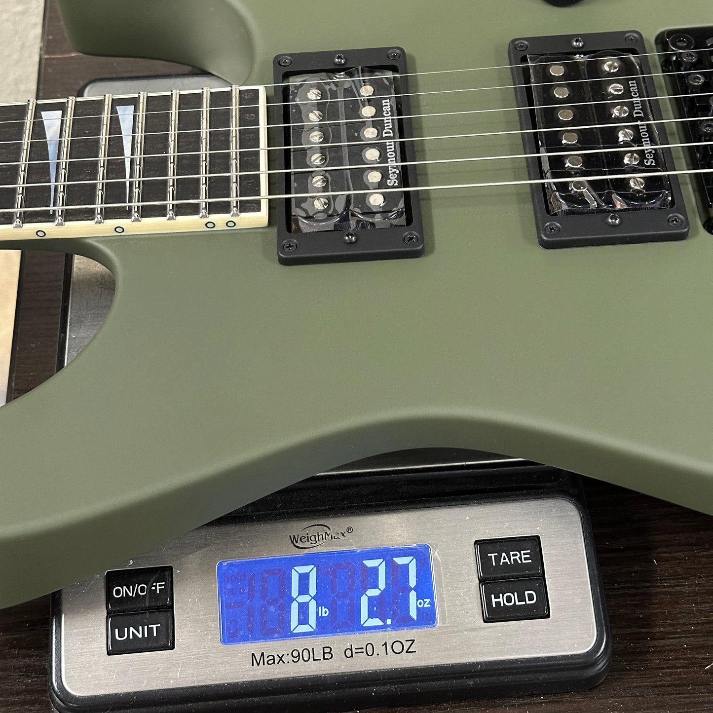 Green electric guitar on a digital scale displaying weight