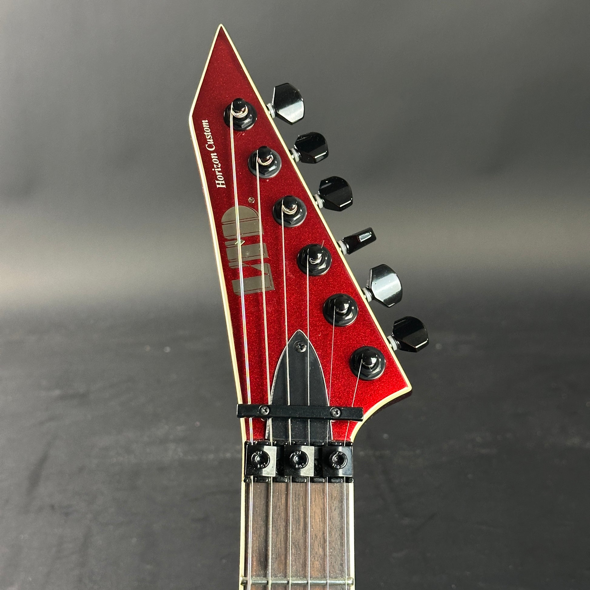 Close-up of a red electric guitar headstock on a gray background