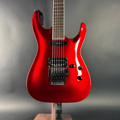 Red electric guitar on a stand against a gray background