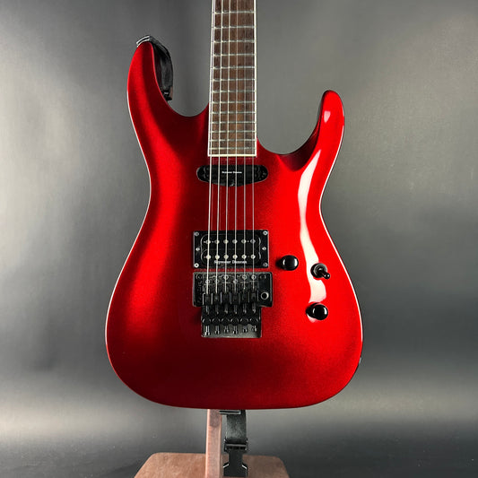 Red electric guitar on a stand against a gray background