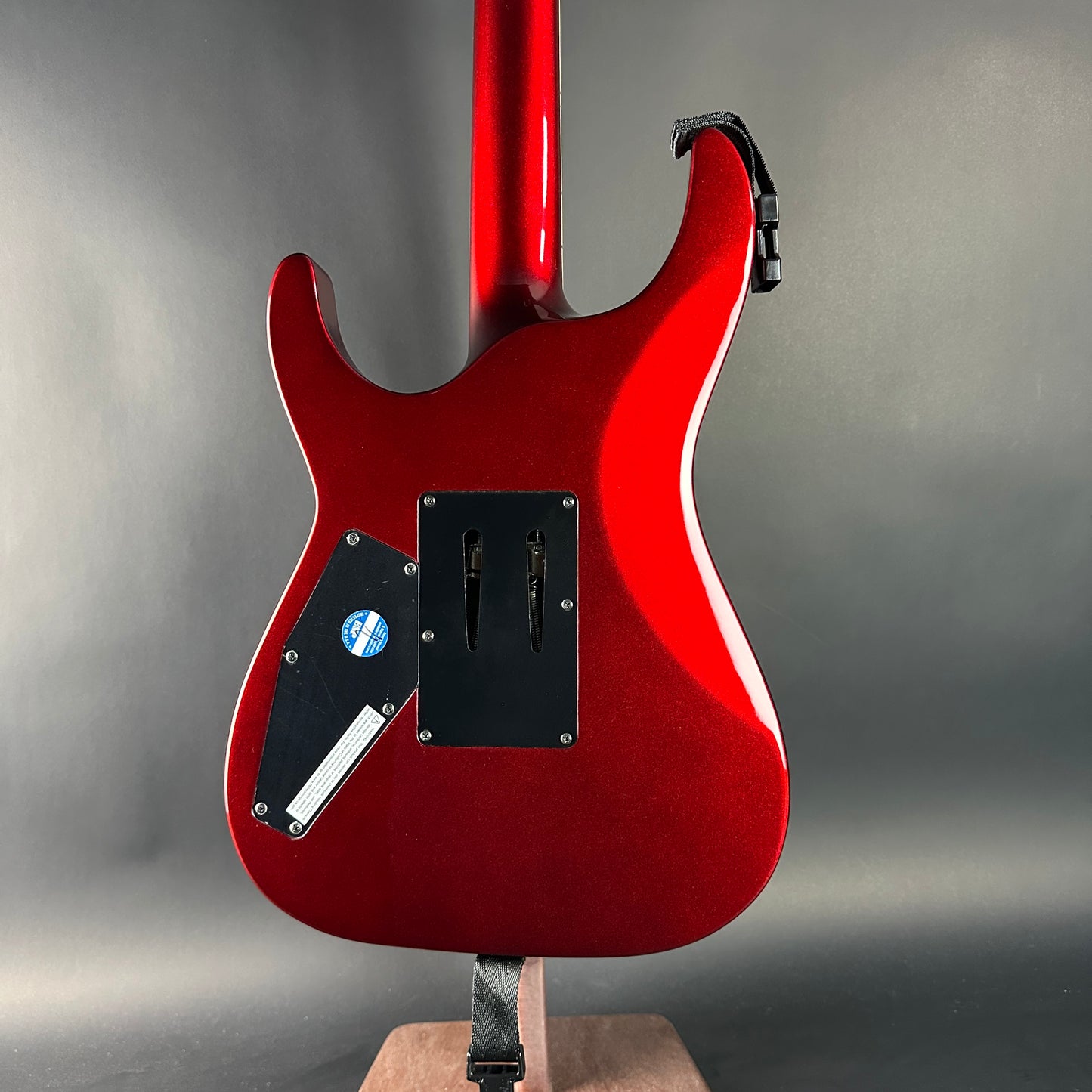 Red electric guitar on a stand against a gray background