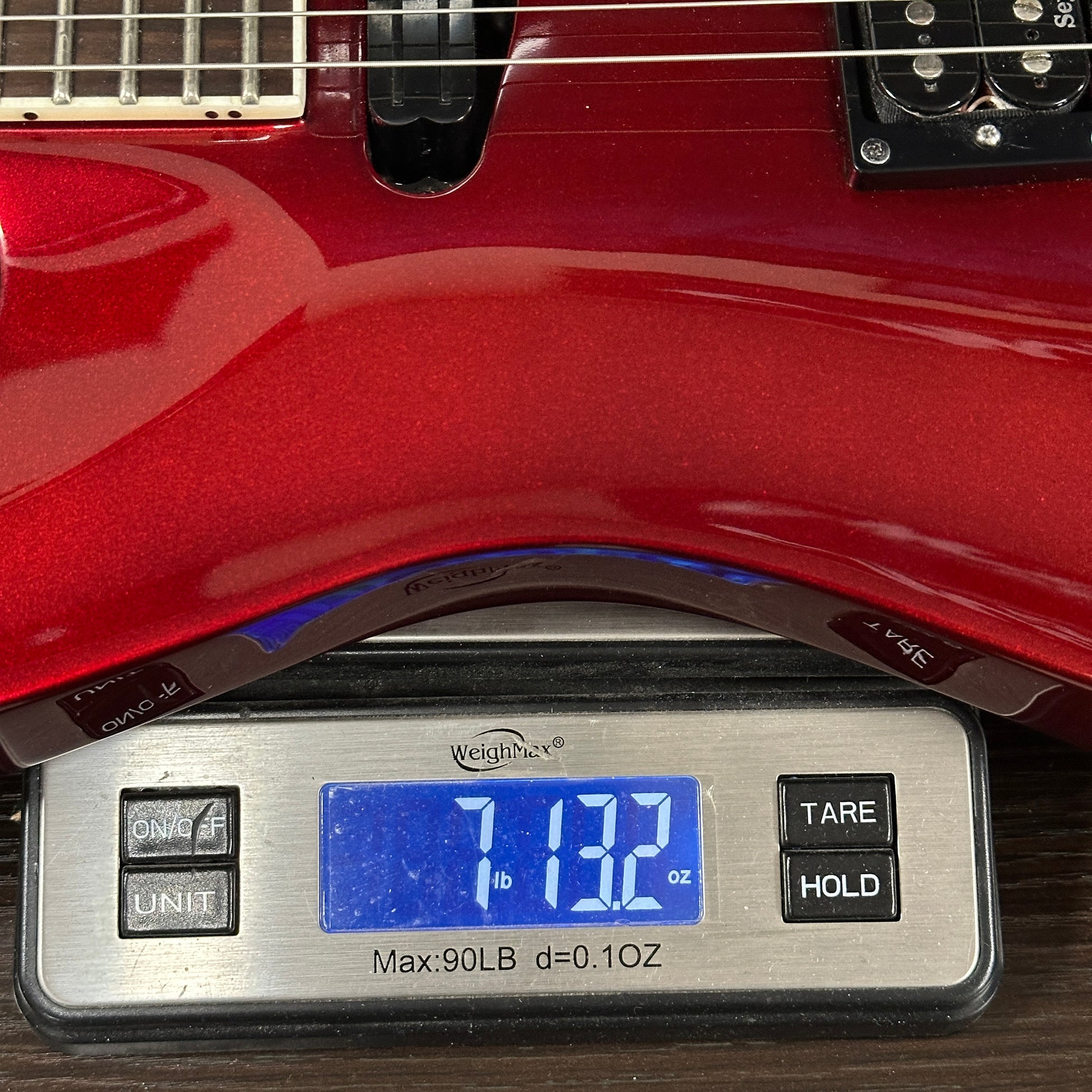 Red electric guitar on a digital scale displaying weight
