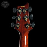Close-up of a guitar headstock with tuning pegs on a black background, featuring the Tone Shop logo.
