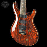 Electric guitar with a wavy wood finish on a black background, featuring the Tone Shop logo.