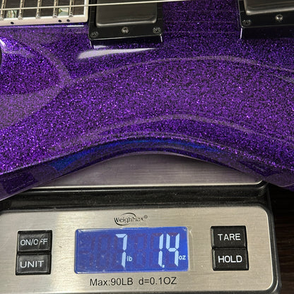 Purple glittery guitar on a digital scale displaying weight.