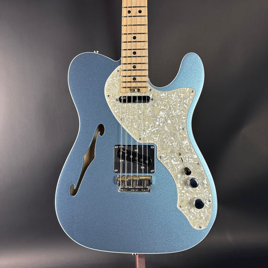 Blue electric guitar with a pearl inlay on a dark background