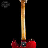 Red electric guitar with a focus on the back of the neck and body against a black background.